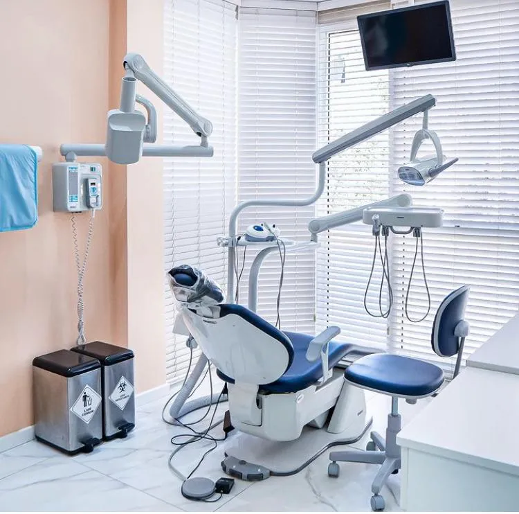 Sala de atendimento com cadeira azul e equipamentos odontológicos